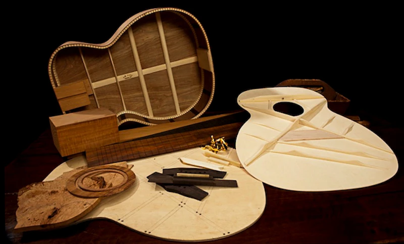 Peças de violão artesanal em diferentes etapas de construção sobre bancada de luthieria
