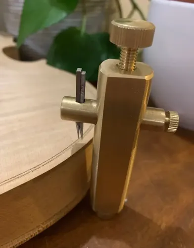 Gramil de lâmina afiada riscando a borda do tampo de abeto antes da passagem da tupia para abrir o canal do binding