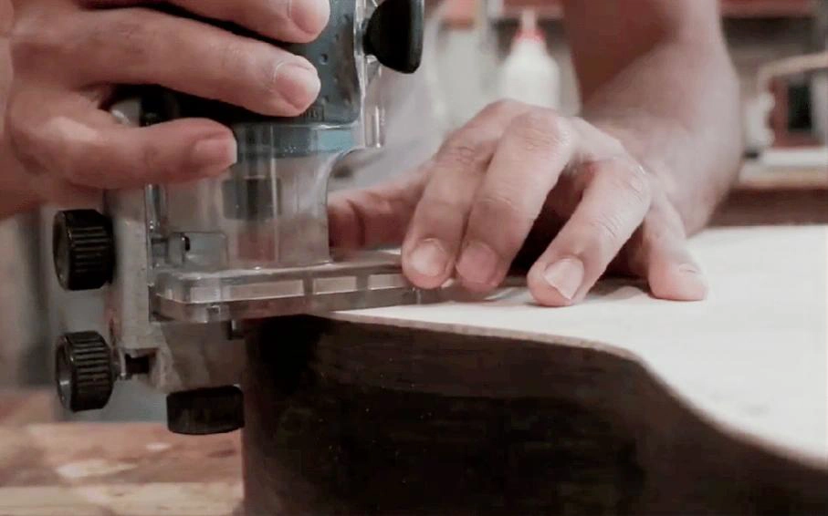 Tupia manual com fresa de topo rolamentada abrindo canal de binding em violão, com o rolamento apoiado na faixa lateral
