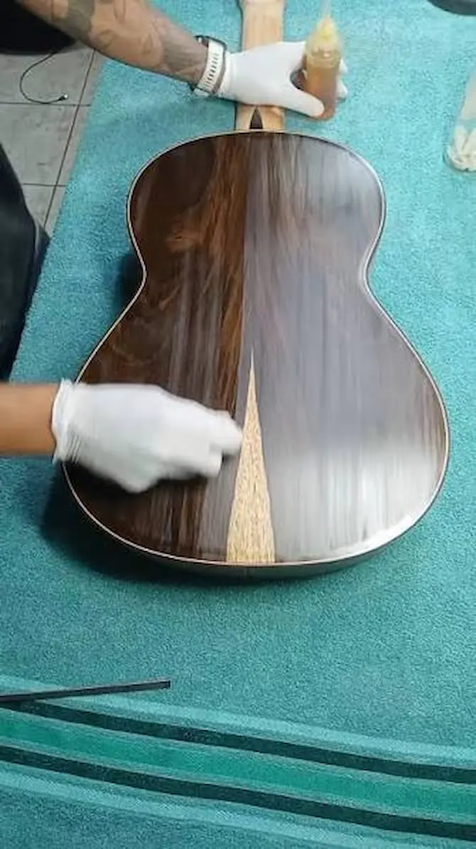 Aplicação de goma-laca com boneca de polimento francês em movimento circular sobre o tampo de um violão