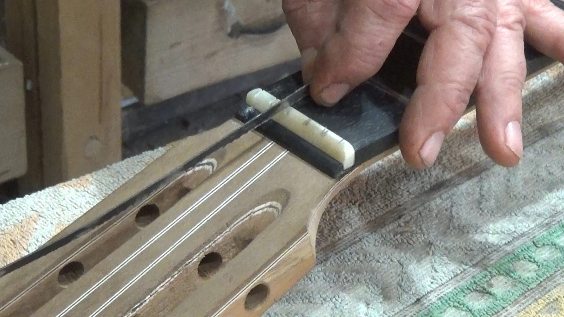 Luthier abrindo canais da pestana de osso bovino com limas específicas para cada diâmetro de corda
