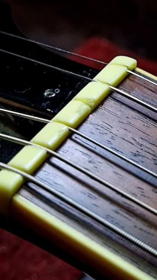 Pestana de violão desgastada sobre bancada de luthier