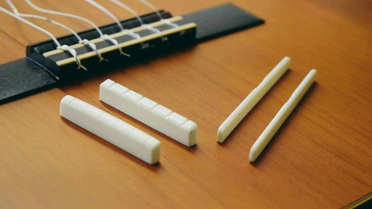 Detalhe da pestana e do rastilho de um violão artesanal com cordas de aço